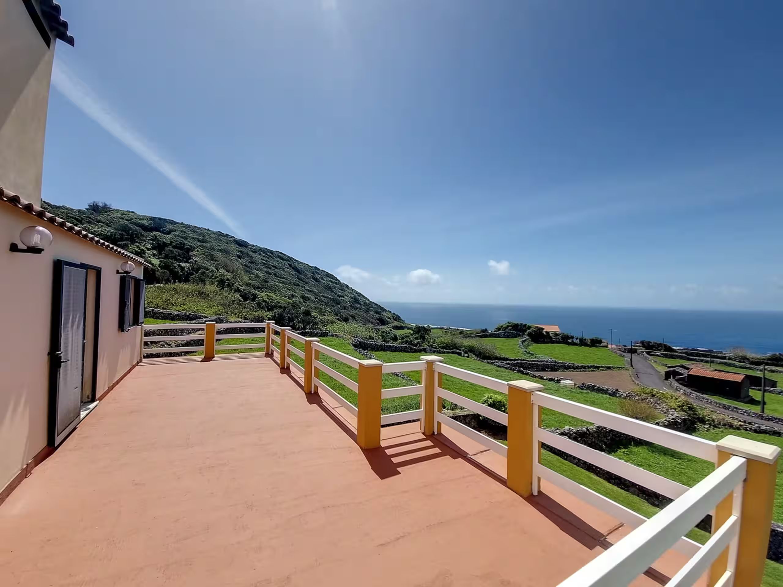 The terrace looking along the railing to the hillside and the ocean beyond